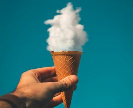man holding ice cream cone under cloud