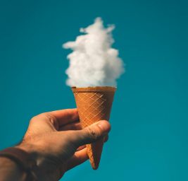 man holding ice cream cone under cloud