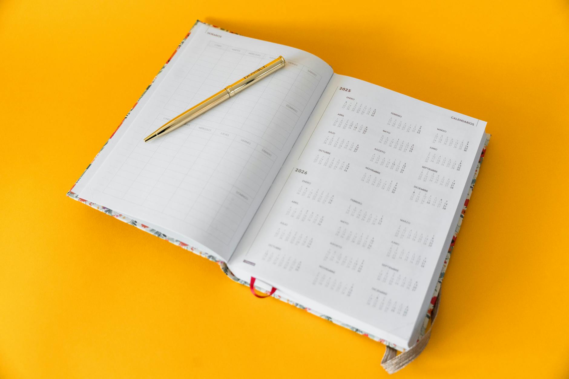 elegant open planner with golden pen on yellow background