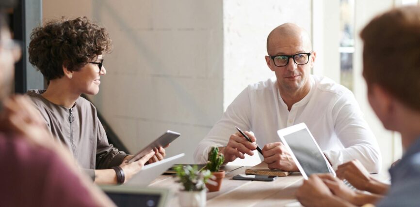photo of man sitting in front of people