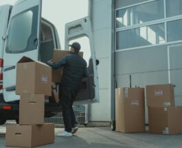 man in blue jacket and blue denim jeans sitting on brown cardboard box