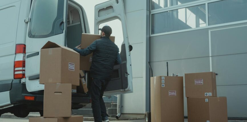 man in blue jacket and blue denim jeans sitting on brown cardboard box