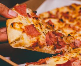 close up photo of person holding pizza
