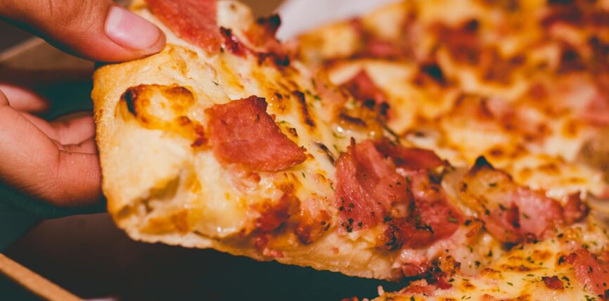 close up photo of person holding pizza