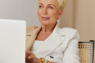 woman in white blazer holding a laptop
