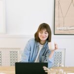 woman drinking coffee and looking at a laptop