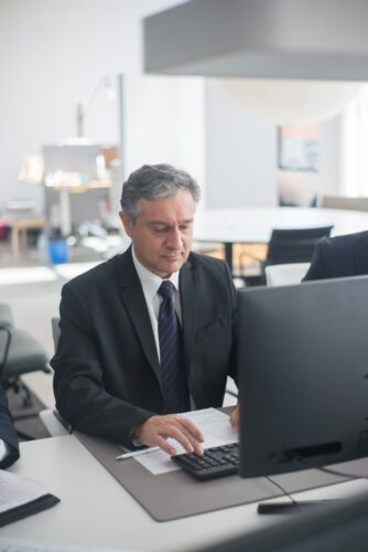 man in black suit sitting at his desk and working