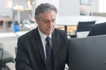 man in black suit sitting at his desk and working