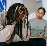 unrecognizable desperate black man with attentive girlfriend at home