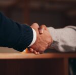 a person in black long sleeve shirt shaking the hands of a person in gray long sleeve shirt