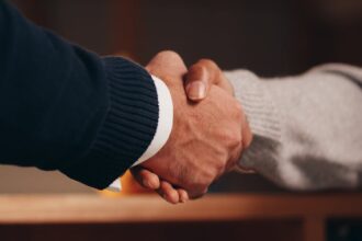 a person in black long sleeve shirt shaking the hands of a person in gray long sleeve shirt