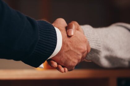 a person in black long sleeve shirt shaking the hands of a person in gray long sleeve shirt