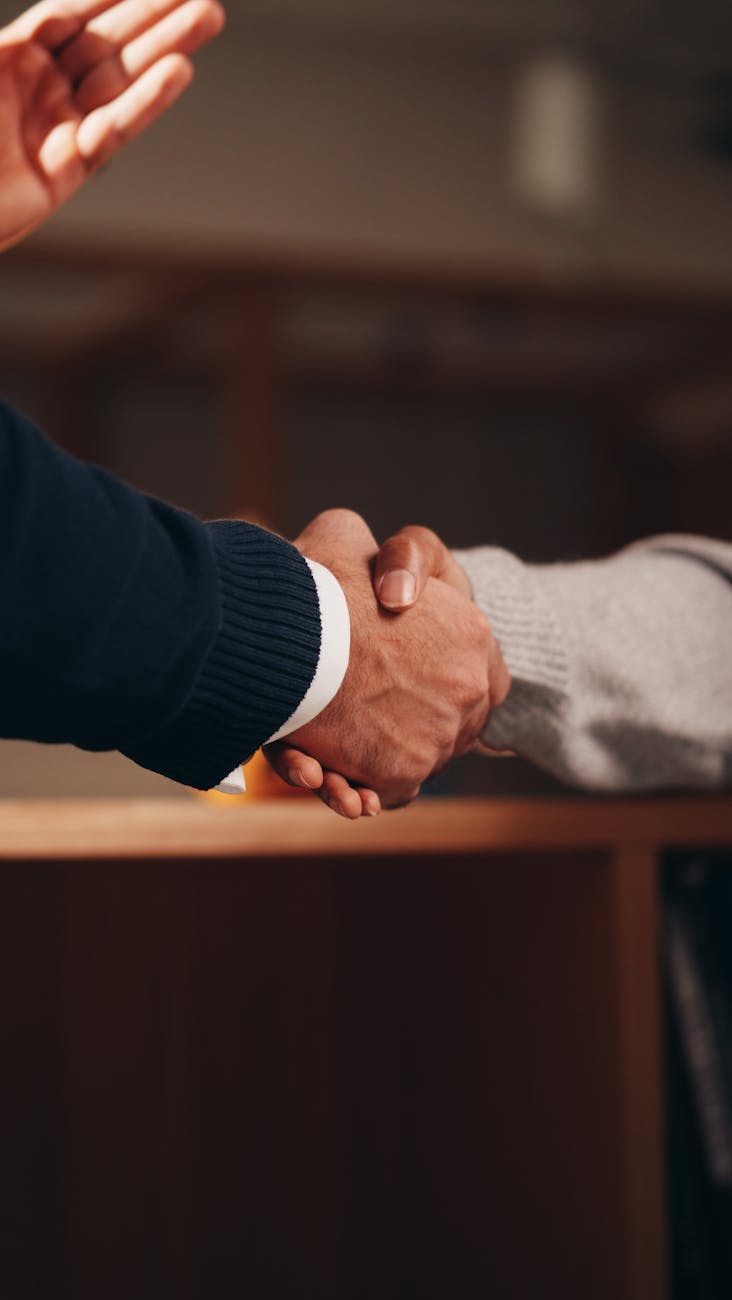 a person in black long sleeve shirt shaking the hands of a person in gray long sleeve shirt