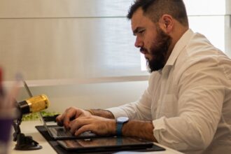 man in shirt sitting and working on laptop