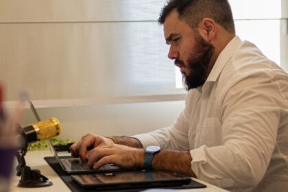 man in shirt sitting and working on laptop
