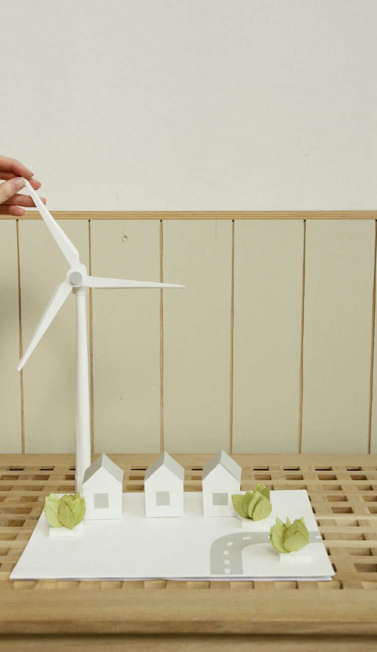 a scale model of houses and wind turbine on cardboard