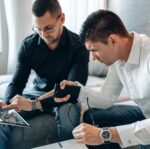 two men pointing at ipad screen