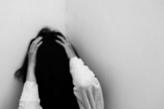 depressed woman sitting in room corner