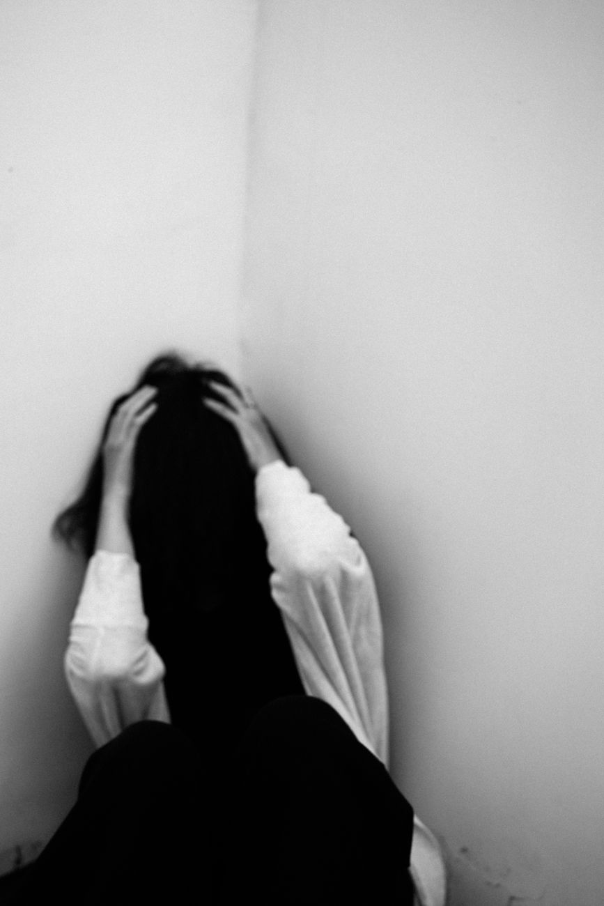 depressed woman sitting in room corner