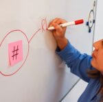 employee drawing on a whiteboard with a hashtag sticky note
