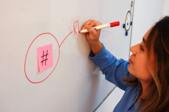 employee drawing on a whiteboard with a hashtag sticky note