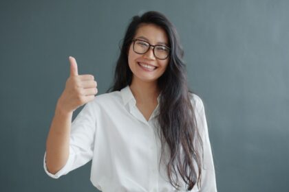 confident woman giving thumbs up in white shirt
